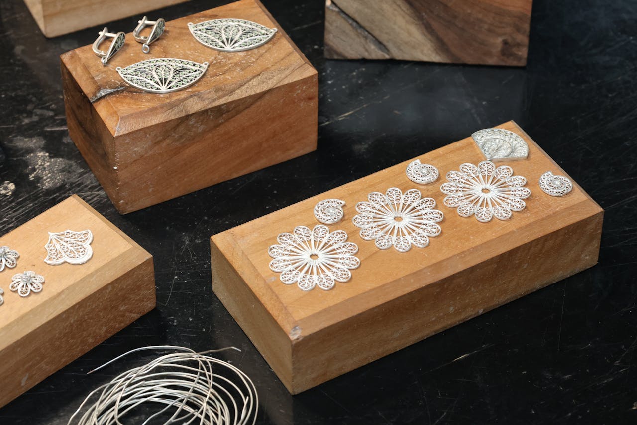 Elegant silver filigree jewelry displayed on wooden blocks, showcasing craftsmanship.